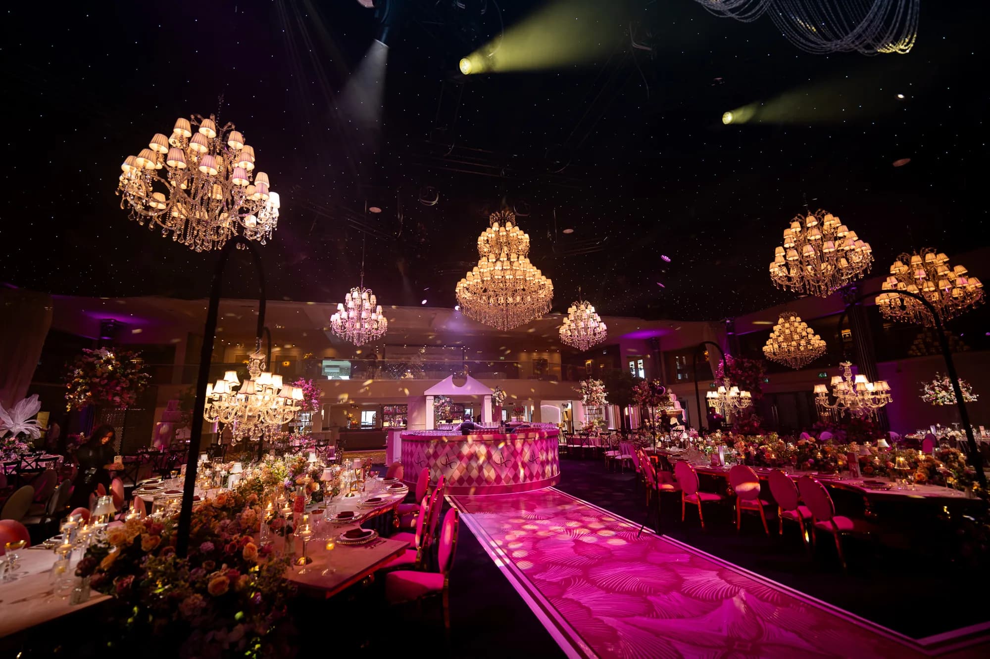 Printed pink walkway leading to a circular bar beneath chandeliers at Dallas Burston Polo Club