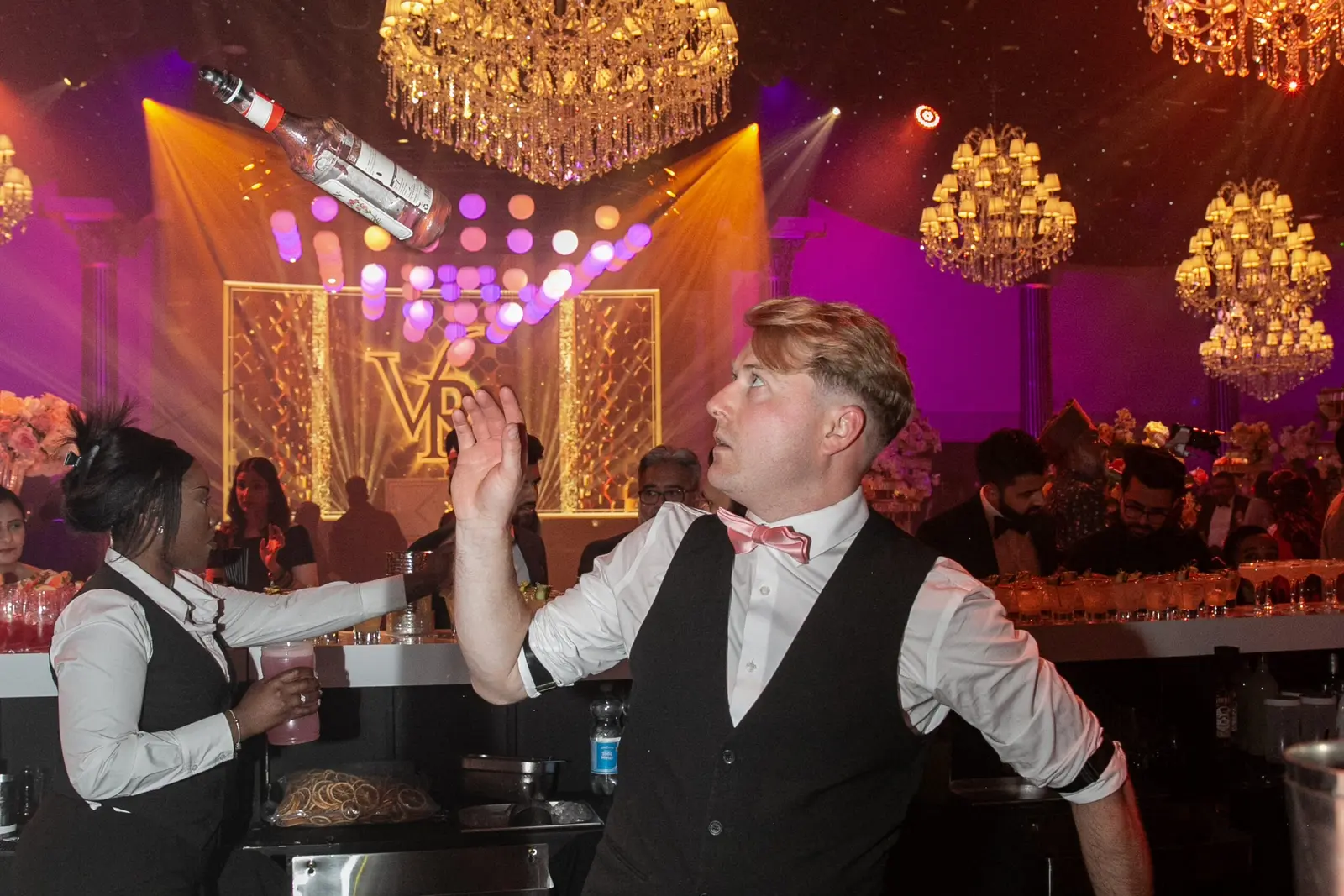 Guests dancing beneath chandeliers and orange stage lighting at Dallas Burston Polo Club