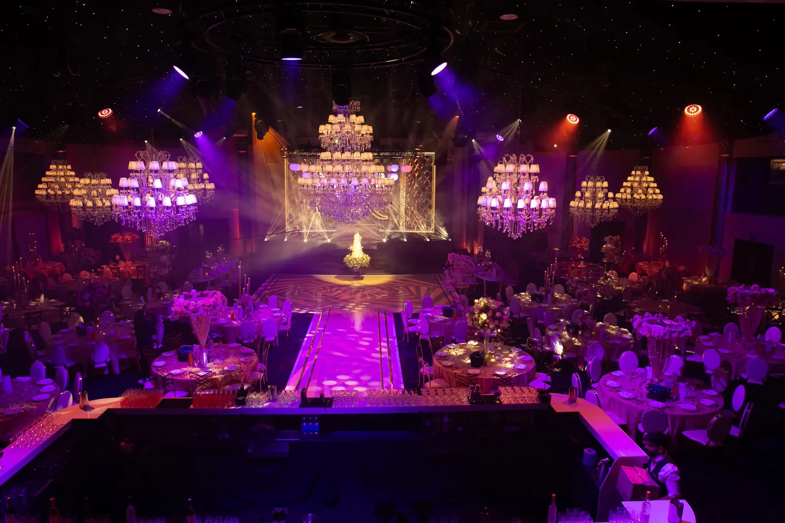 Wedding reception seen from the bar towards a brightly lit stage | Dallas Burston Polo Club Wedding reception seen from the bar towards a brightly lit stage at Dallas Burston Polo Club