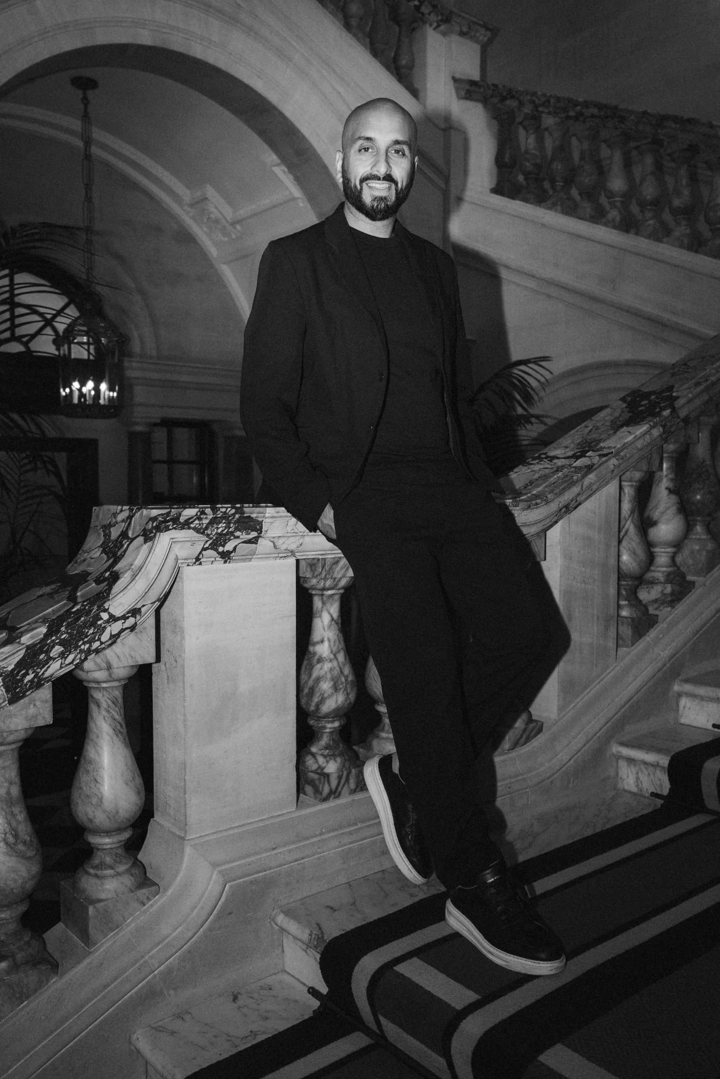 Black and white photo of DJ H of Kudos Music seated on a marble staircase balustrade