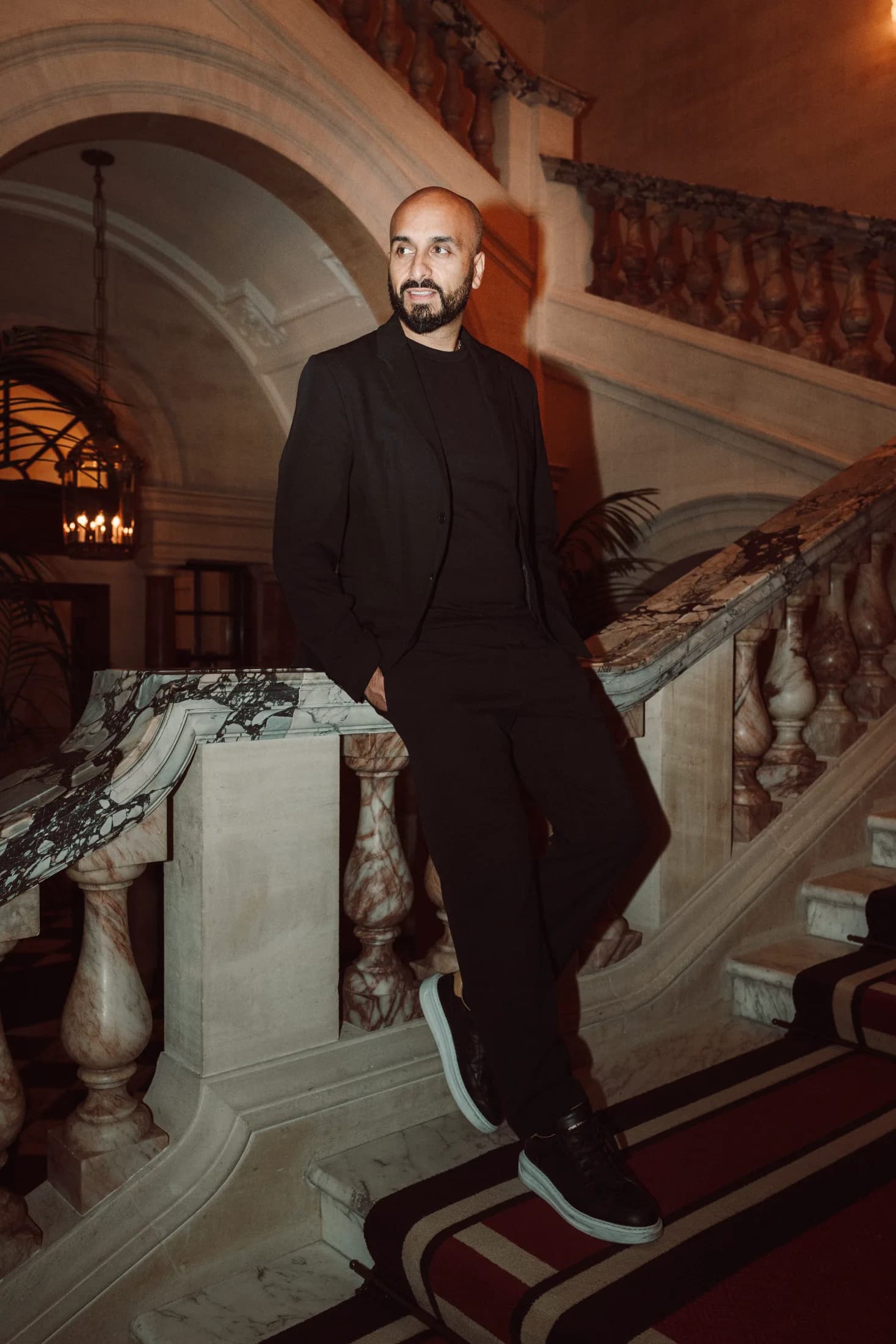 DJ H of Kudos Music leaning against a marble staircase at an evening event