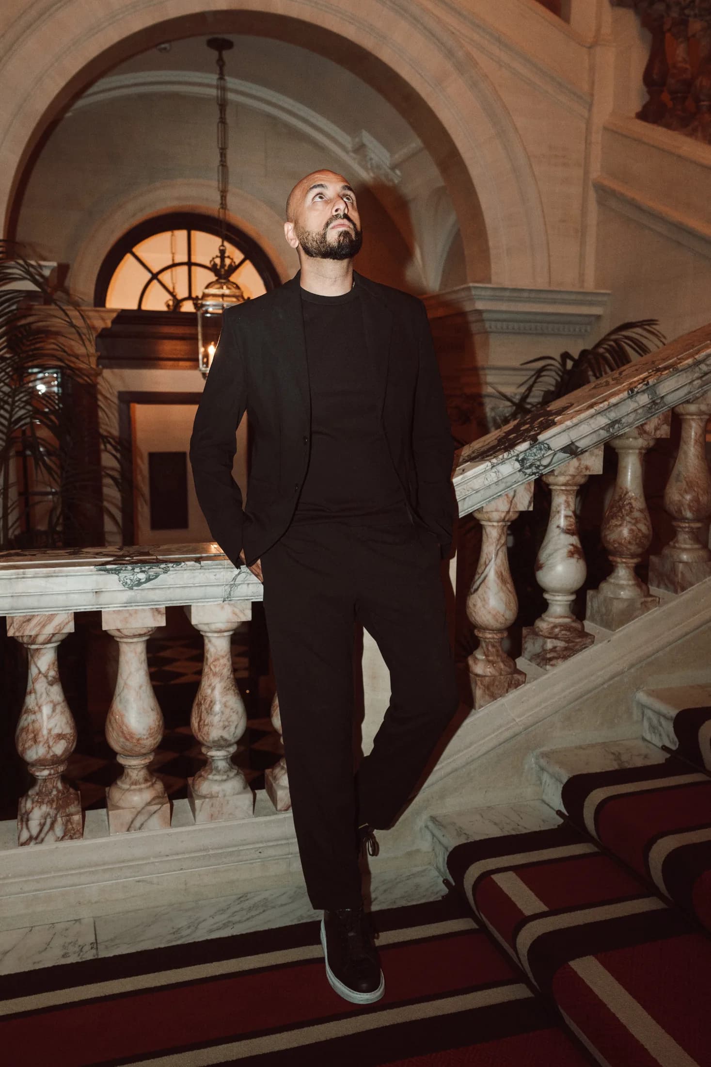 DJ H of Kudos Music standing in front of an arched window on a grand staircase