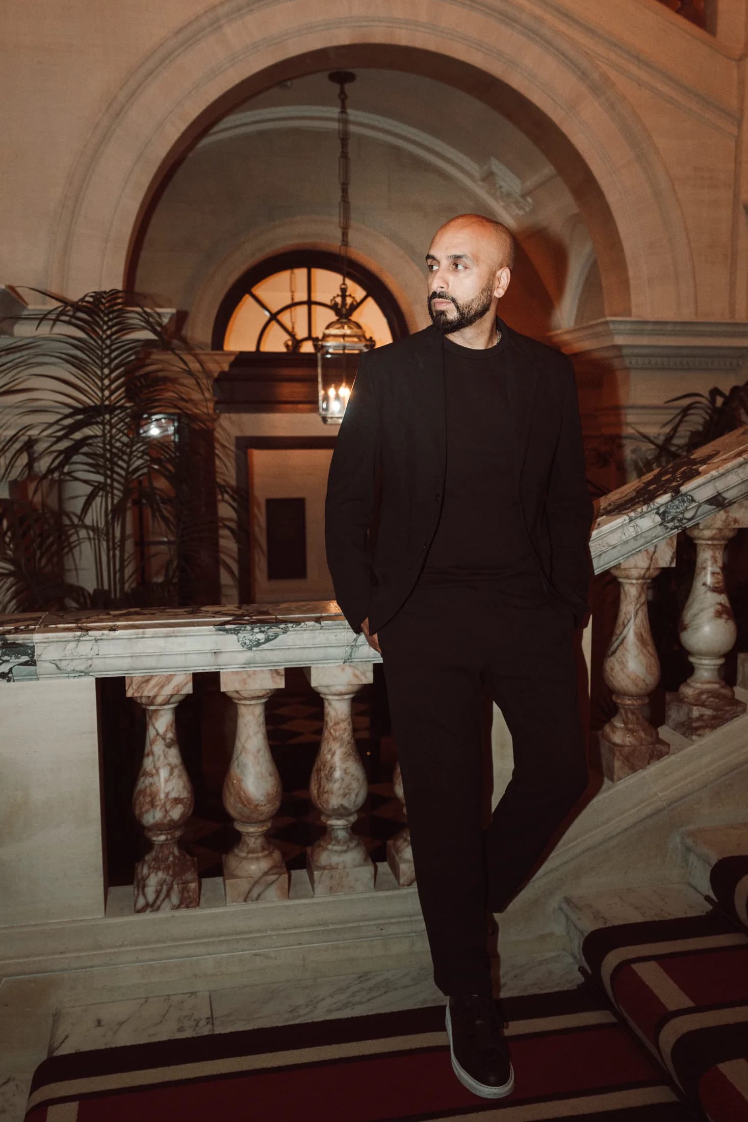 DJ H of Kudos Music smiling on a grand marble staircase at a luxury venue