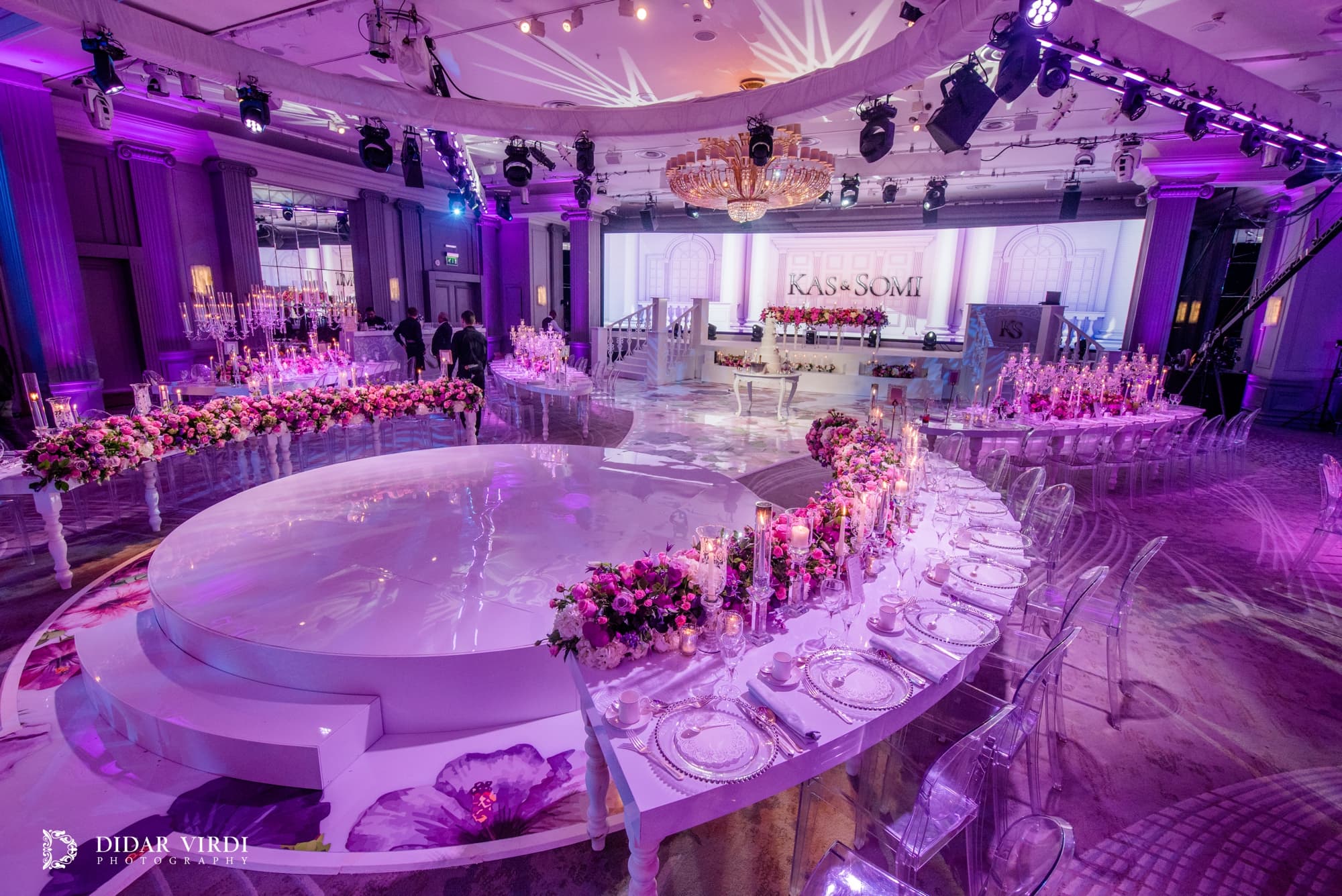 White circular first-dance stage surrounded by curved tables, candles and pink flowers at Grosvenor House Ballroom.