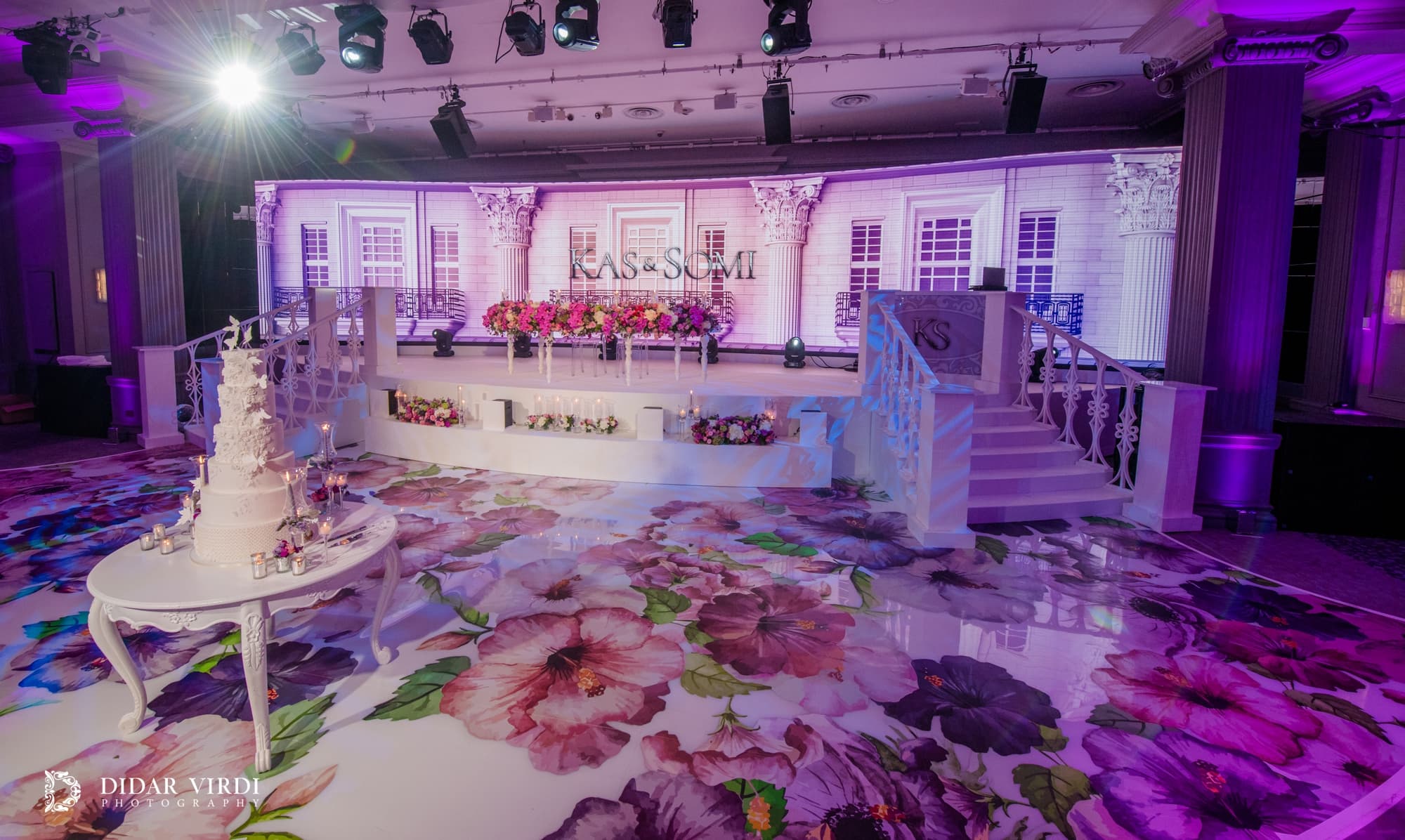 A floral route to the stage Floral wedding walkway leading past the cake to the white staircase set at Grosvenor House Ballroom.