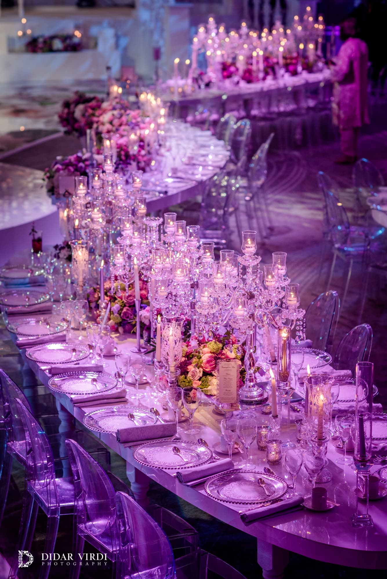 Candlelit curves A curved wedding table lined with candles and pink flowers beside the first-dance stage at Grosvenor House Ballroom.
