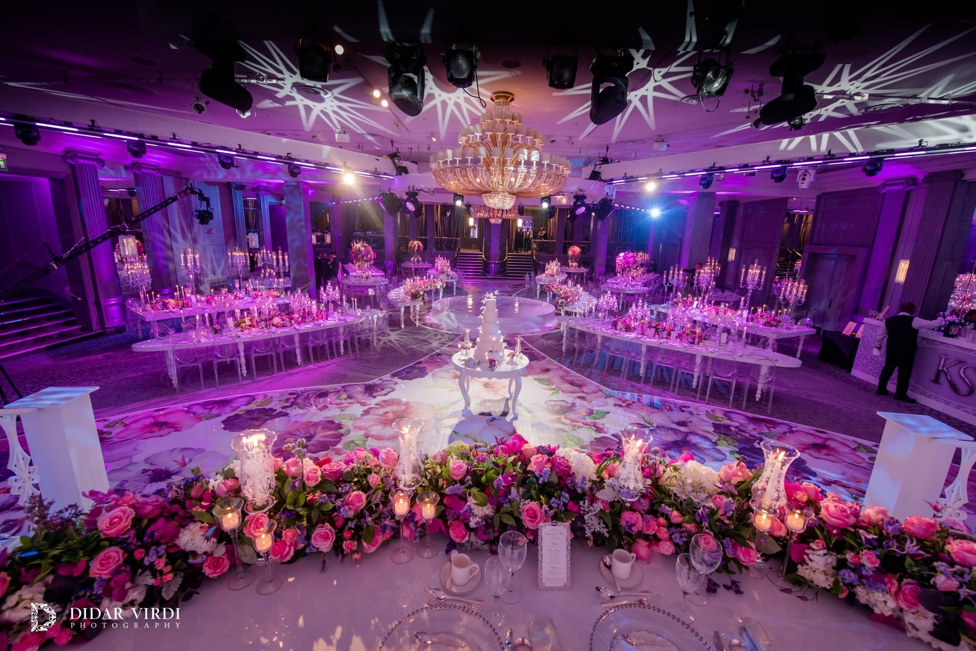Pattern above the celebration Star-shaped light patterns above the chandeliers, wedding tables and floral walkway in Grosvenor House Ballroom.