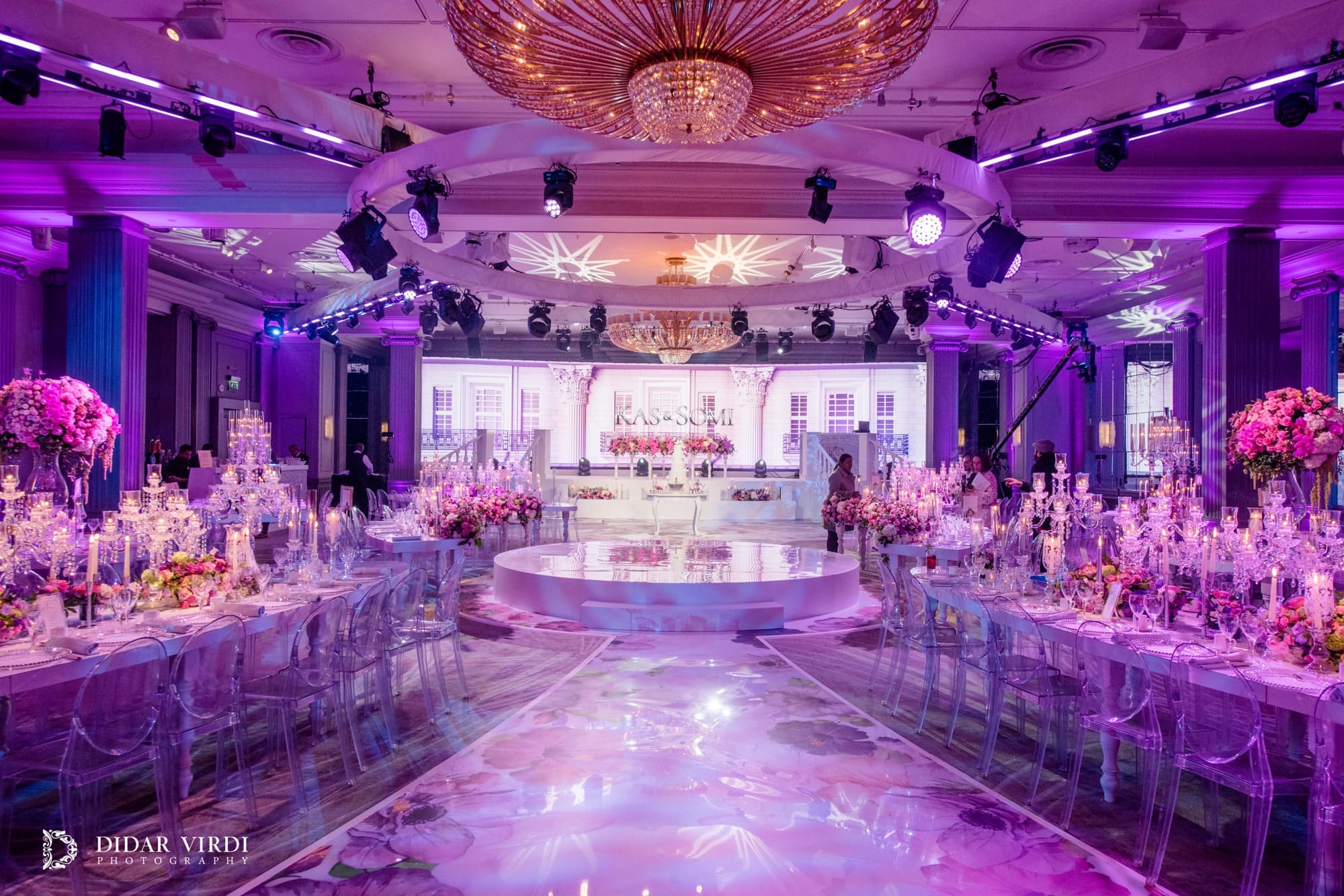 The view towards the first dance Floral walkway between candlelit wedding tables leading towards the white first-dance stage at Grosvenor House.
