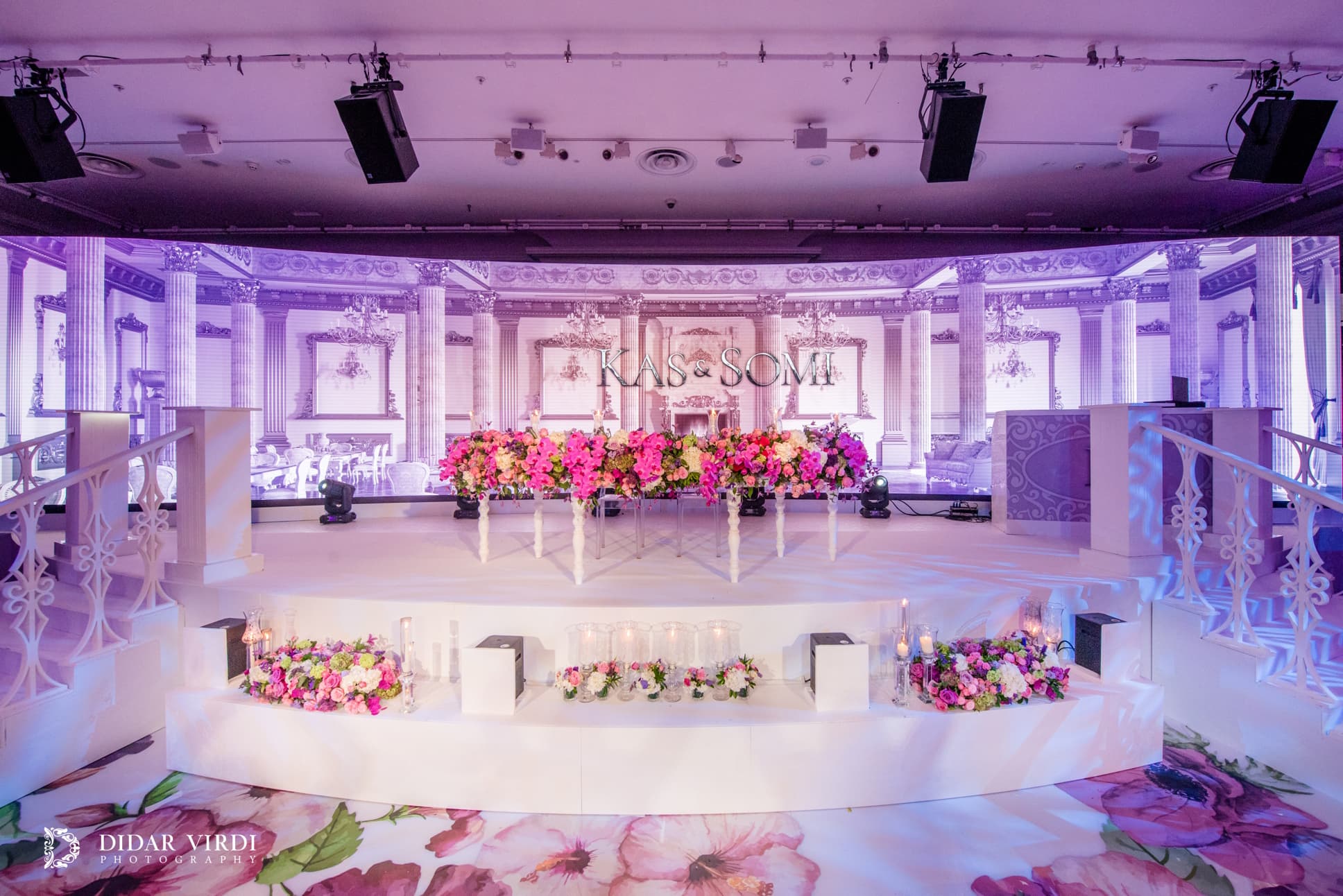 The white wedding backdrop White balustrades and curved stage tiers in front of an architectural LED wedding backdrop at Grosvenor House.