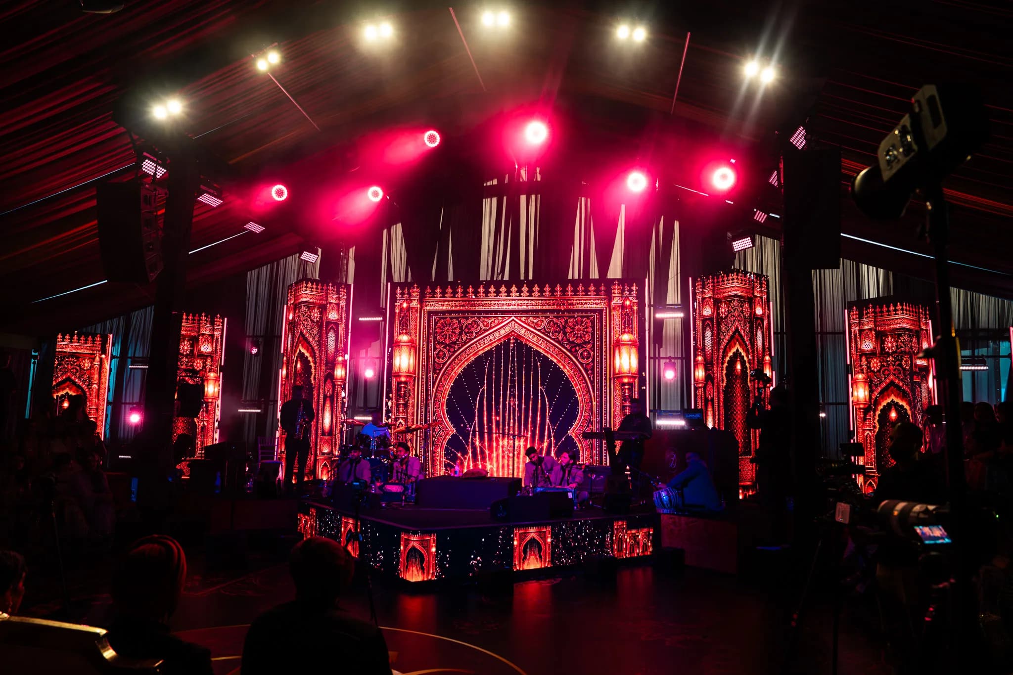 The whole stage at Eksimran and Dilraj's sangeet at the Malhi Residence, carved arches and LED screens under a rig of moving lights