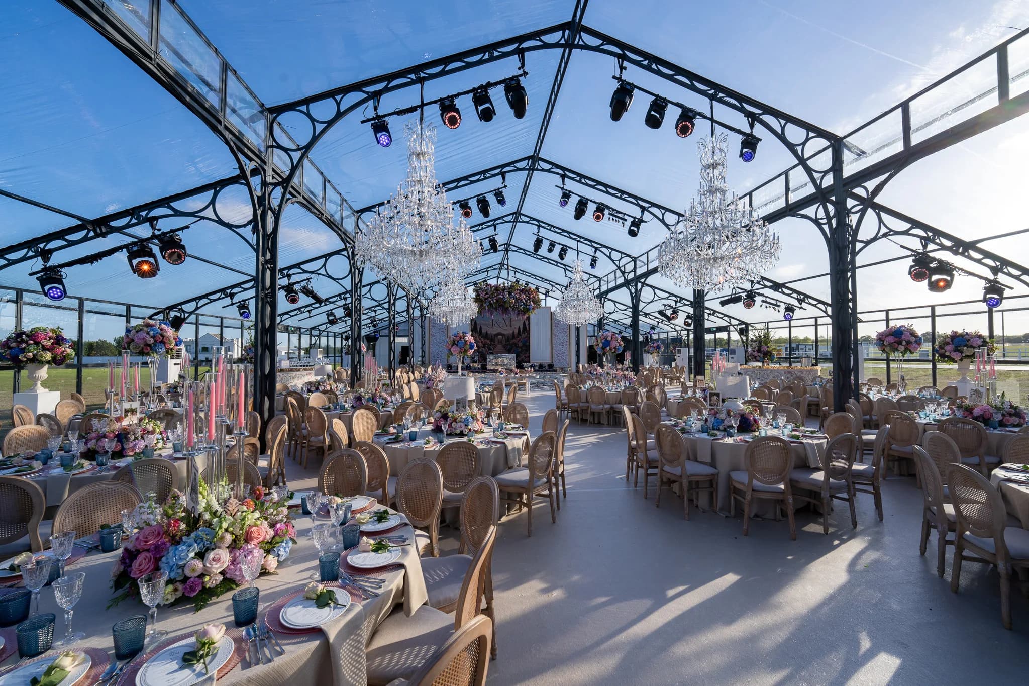 Chandelier canopy and floral table settings inside the glass wedding marquee | Dallas Burston Polo Club Chandelier canopy and floral table settings inside the glass wedding marquee at Dallas Burston Polo Club