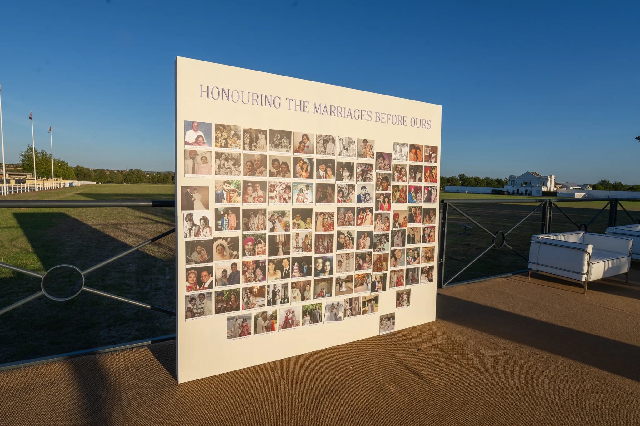 A photo wall on the polo grounds reading Honouring The Marriages Before Ours, covered in family wedding photographs, at Jeevan and Megha's wedding at Dallas Burston Polo Club, Kudos Music