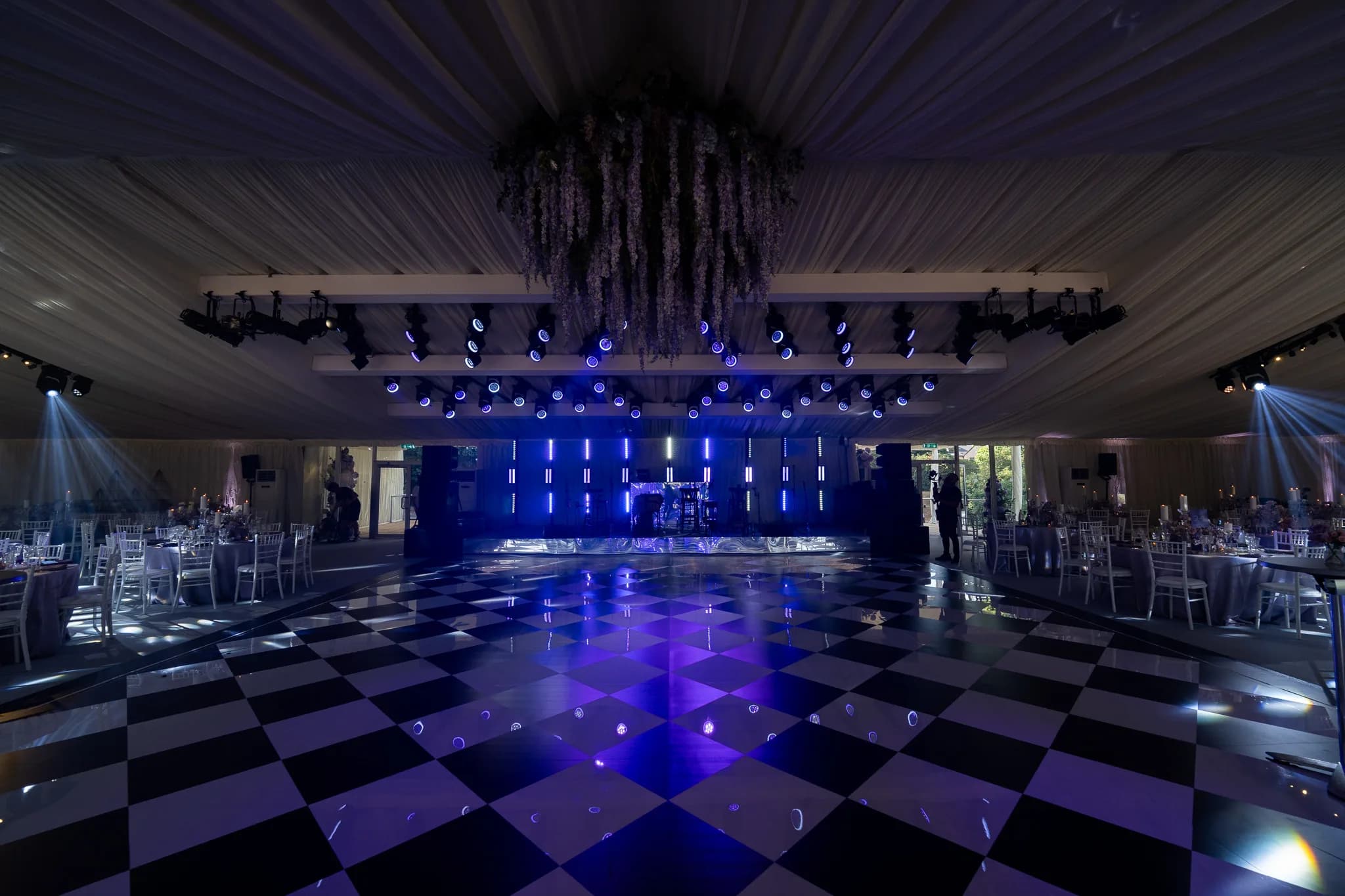 Mirror dancefloor beneath a suspended floral installation and blue lights | Pennyhill Park Mirror dancefloor beneath a suspended floral installation and blue lights at Pennyhill Park