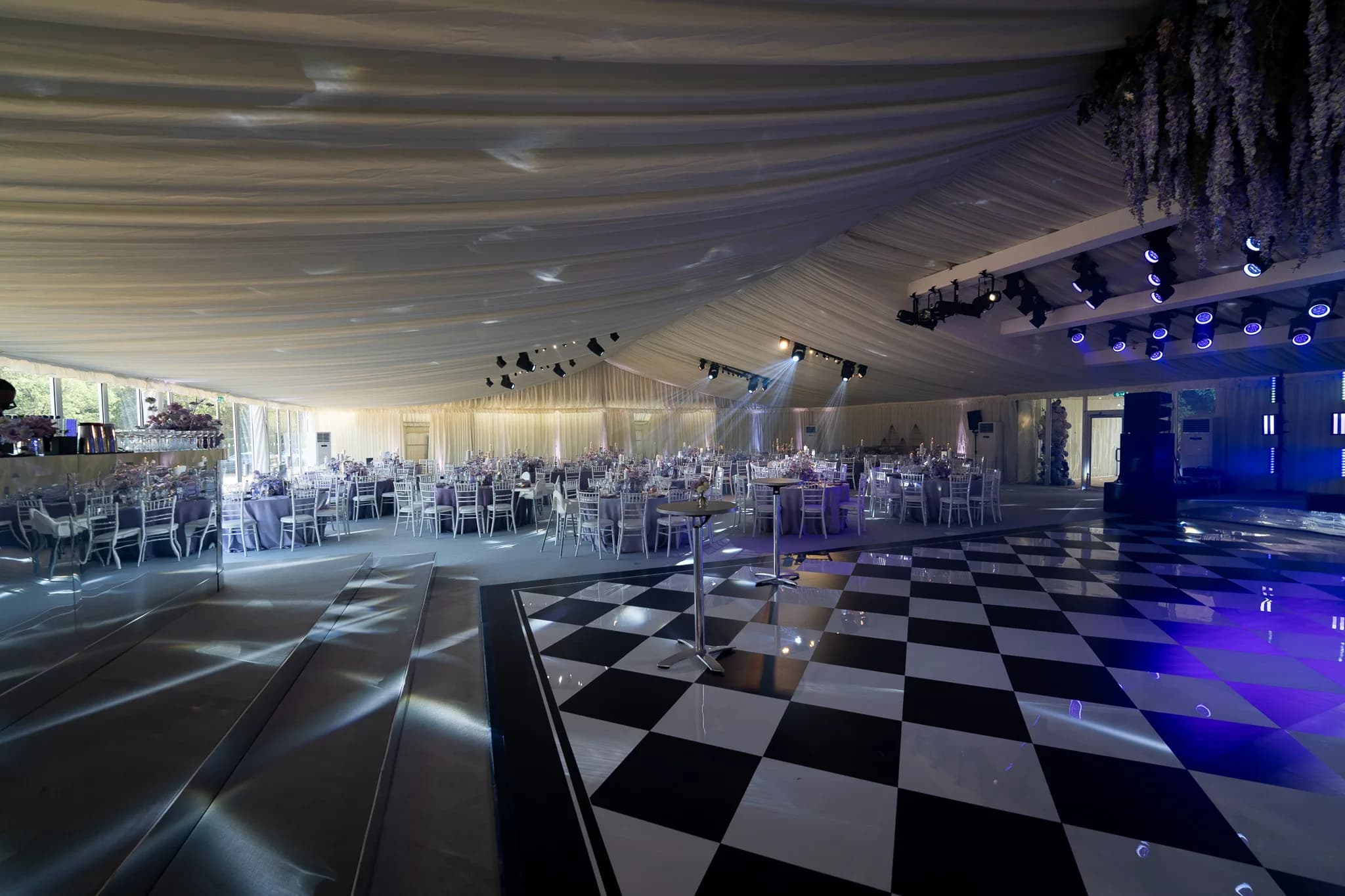 White marquee interior with reception tables beside the chequerboard floor | Pennyhill Park White marquee interior with reception tables beside the chequerboard floor at Pennyhill Park