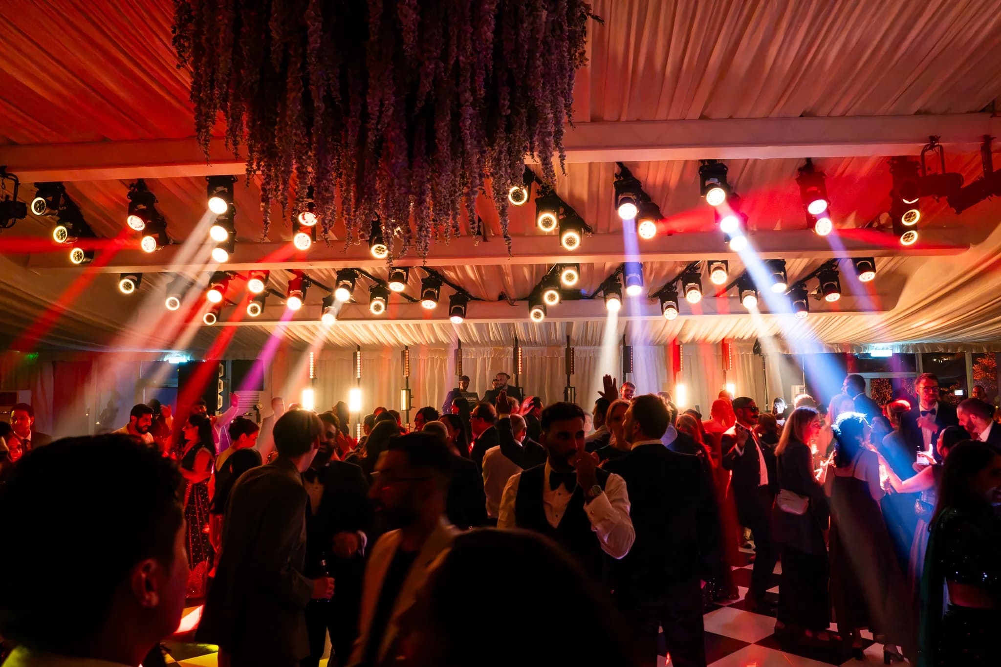 The dancefloor packed under red and blue light, dried florals hanging from the draped marquee ceiling, Lakhita and Satnaam's Pennyhill Park reception, Kudos Music