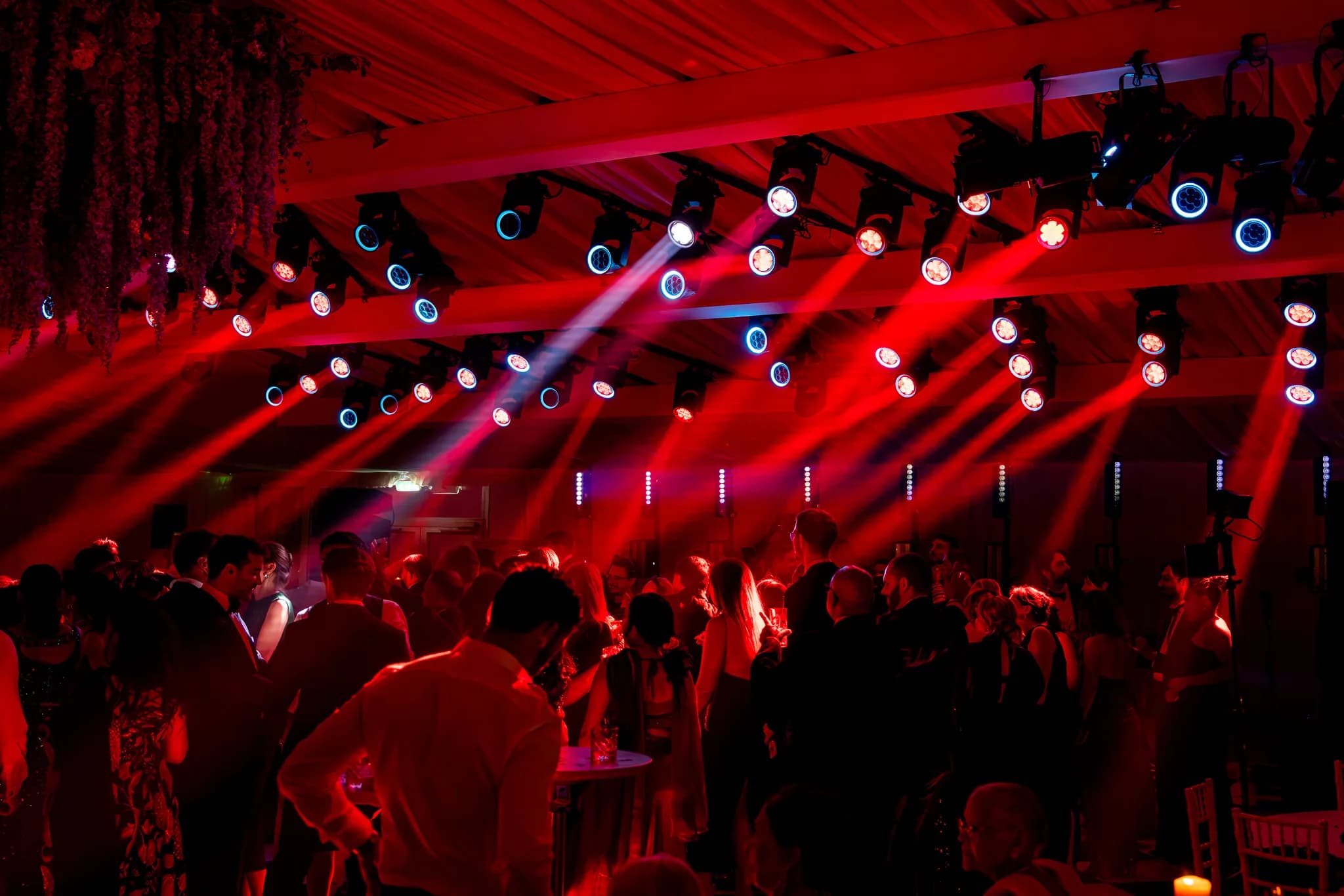 Wedding guests dancing beneath red and white moving beams at Pennyhill Park