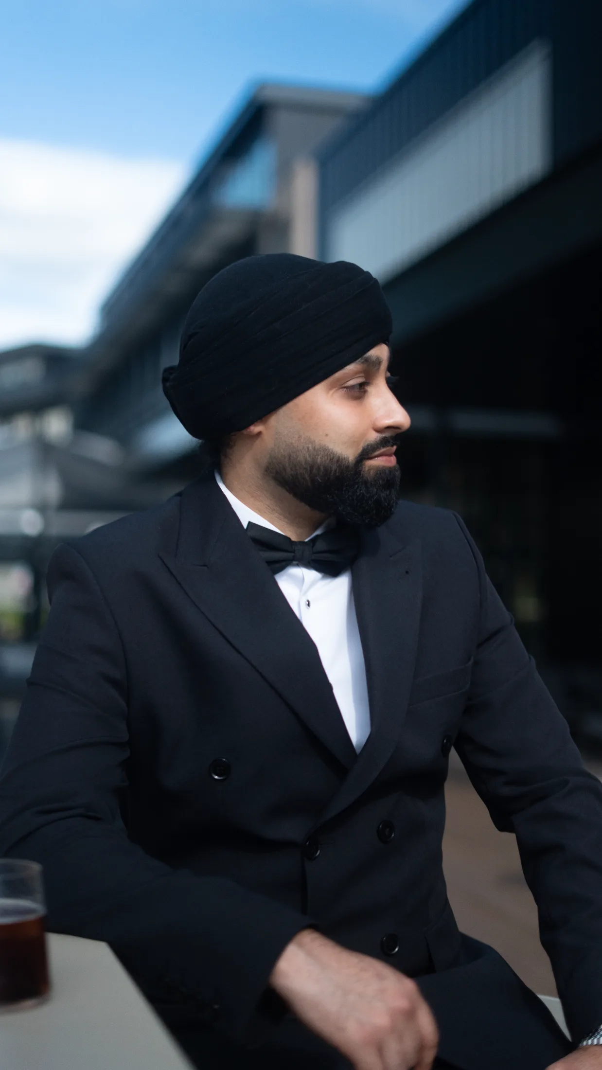 Profile of DJ Harj Matharu of Kudos Music in a black tuxedo and turban outdoors