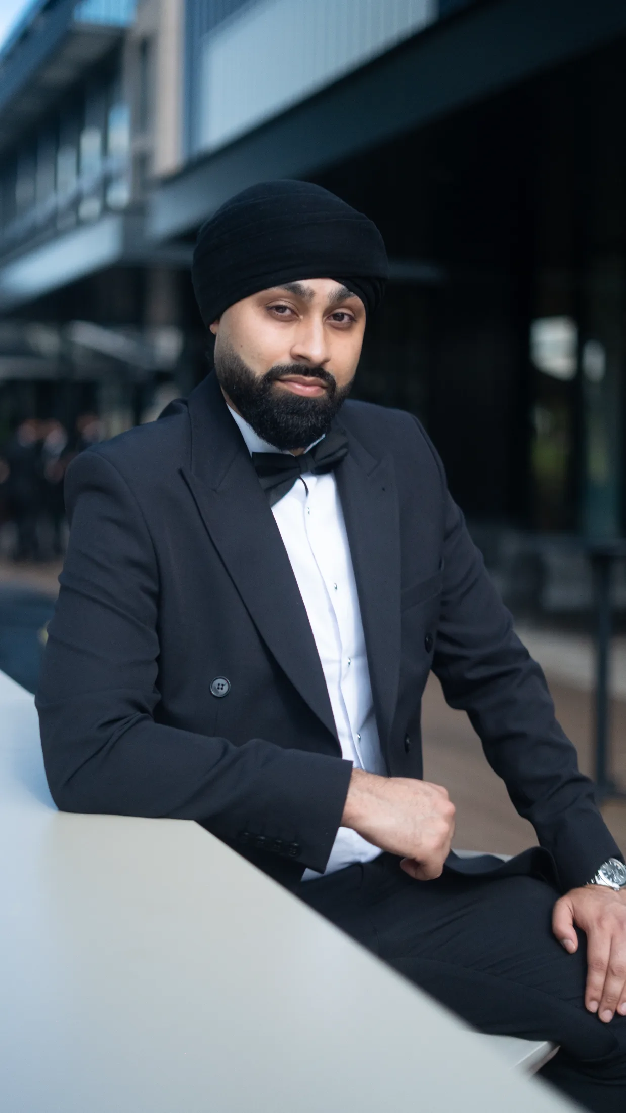 DJ Harj Matharu of Kudos Music in a black tuxedo, resting on a table and looking down