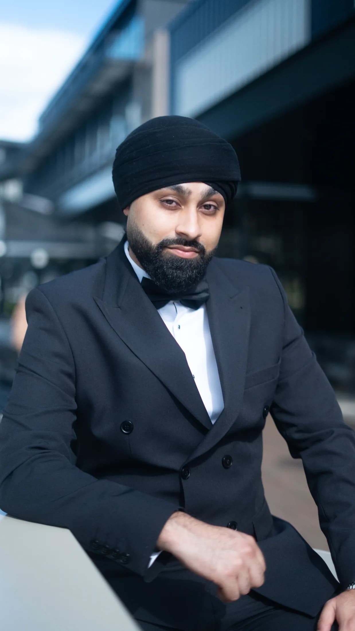 DJ Harj Matharu of Kudos Music in black tie, looking to camera on a city street