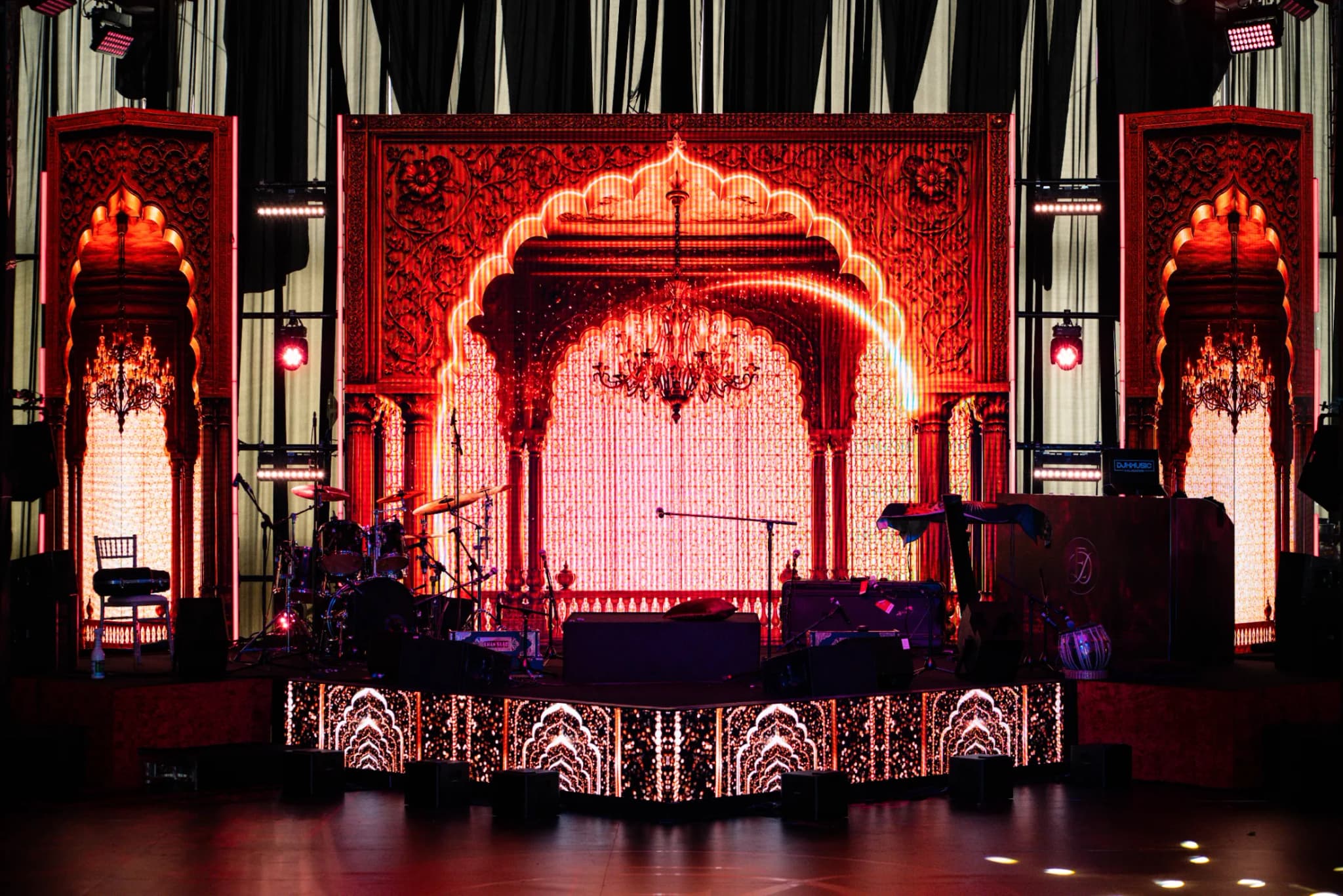 The arched stage and its LED front at Eksimran and Dilraj's sangeet, the band's instruments set and waiting, Kudos Music