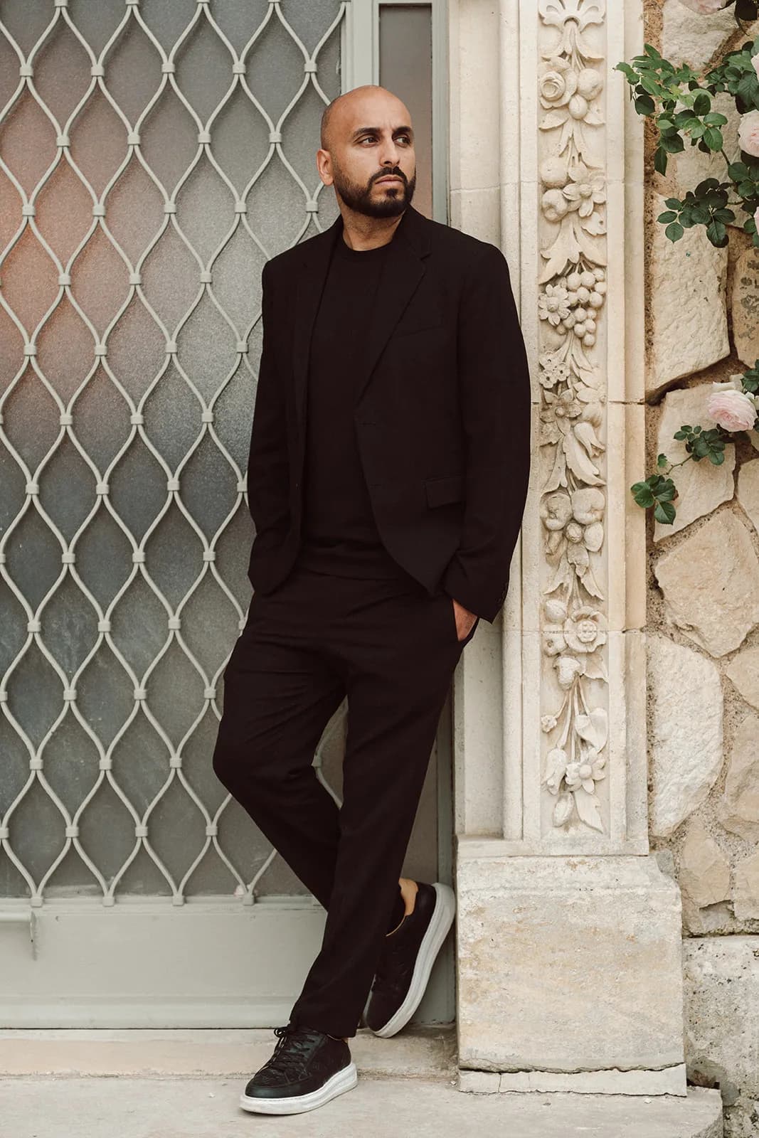 DJ H leaning against an ornate stone column at a wedding