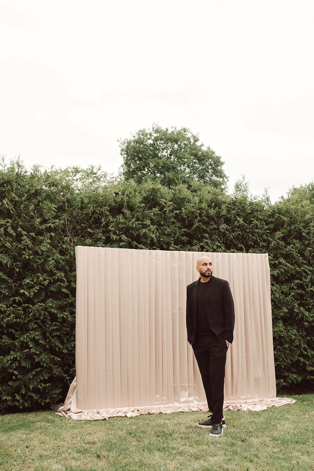 Editorial portrait of DJ H against a draped backdrop