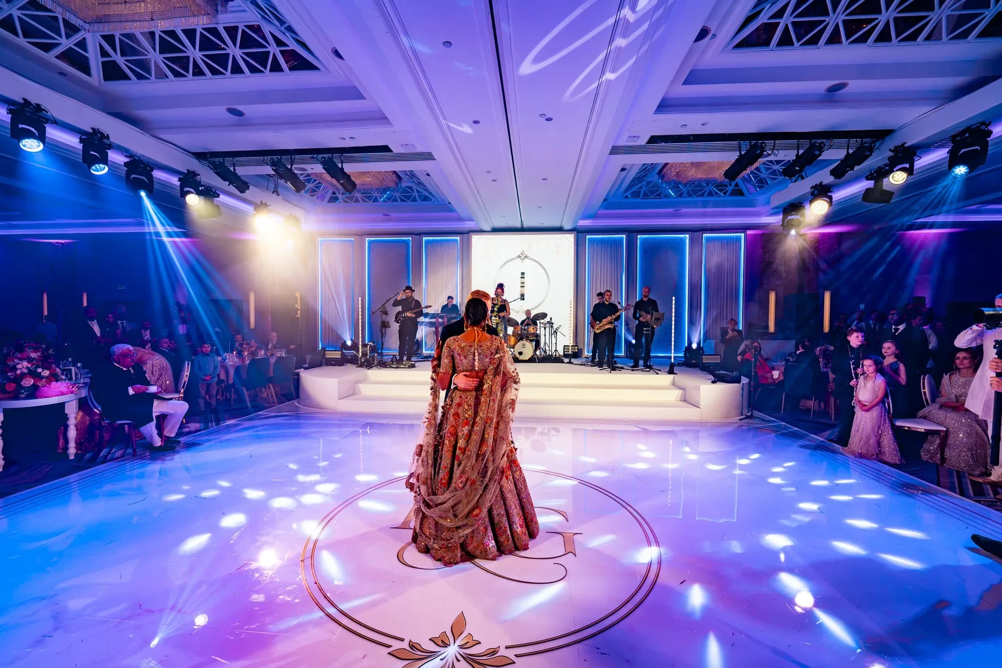 Pooja and Gary in the centre of the ballroom for their first dance, with guests watching from either side.