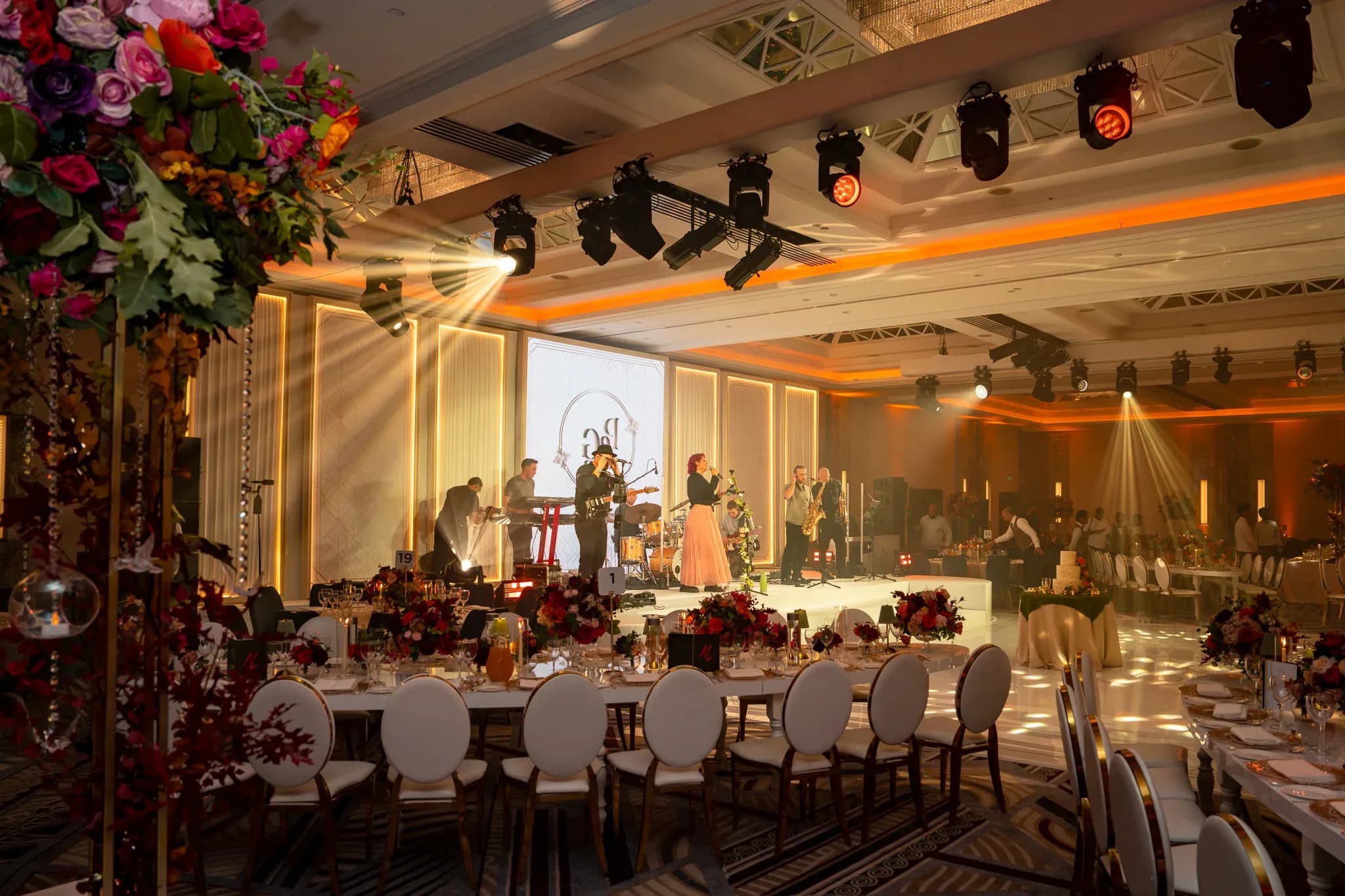 The stage from the guest tables | Royal Lancaster London | Kudos Music Live performers seen past the flowers and dining tables at the Royal Lancaster London reception.