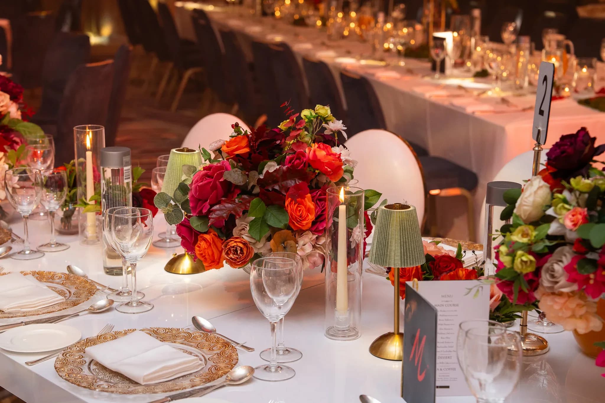 The smaller details | Royal Lancaster London | Kudos Music A green table lamp, red flowers and a place setting on a bespoke white wedding table.