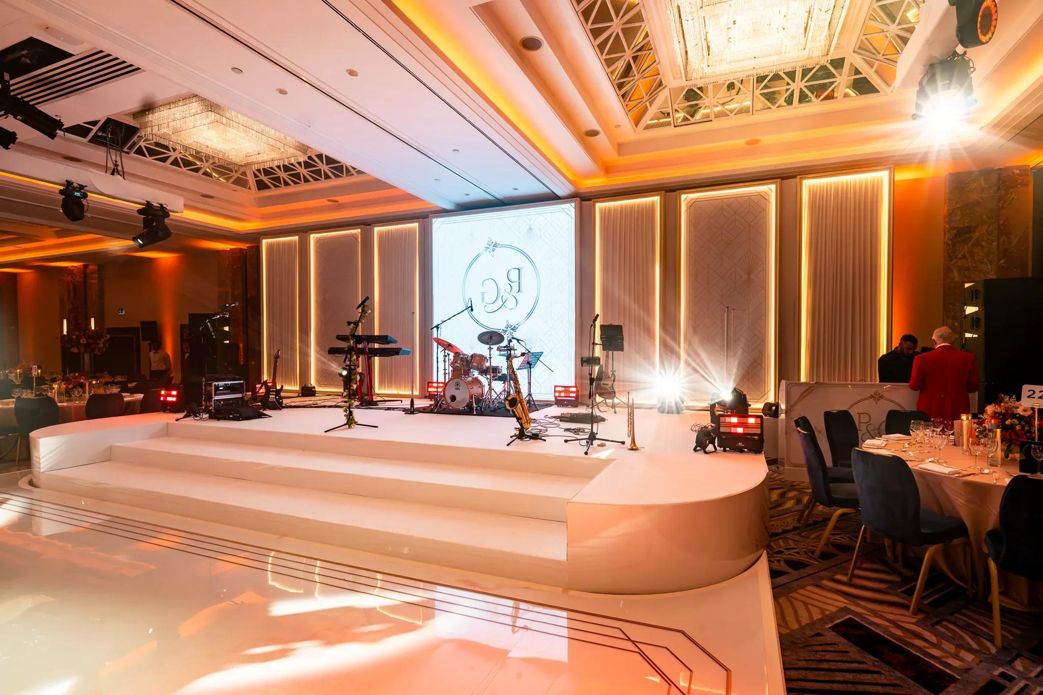 A backdrop for the evening | Royal Lancaster London | Kudos Music Curved white stage steps beneath illuminated panels at the Royal Lancaster London wedding reception.