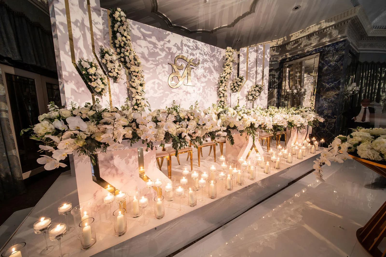 Candlelit head table against a marble-effect backdrop at The Dorchester