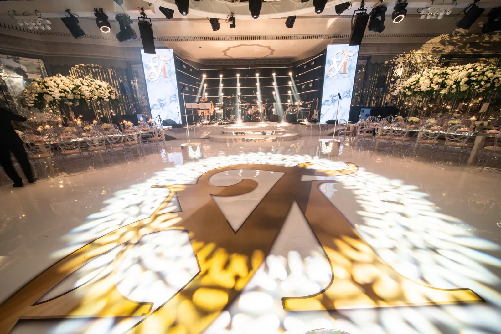 Gold monogrammed white dancefloor with patterned lighting and LED columns at The Dorchester