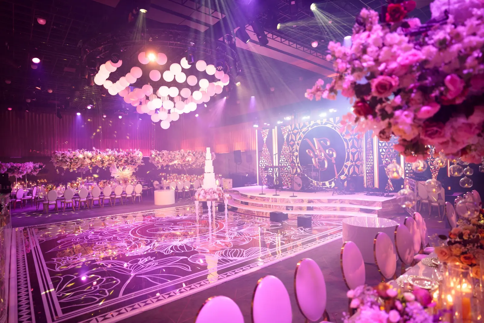 Pink-lit wedding tables surrounding the reflective dancefloor | The Londoner Pink-lit wedding tables surrounding the reflective dancefloor at The Londoner