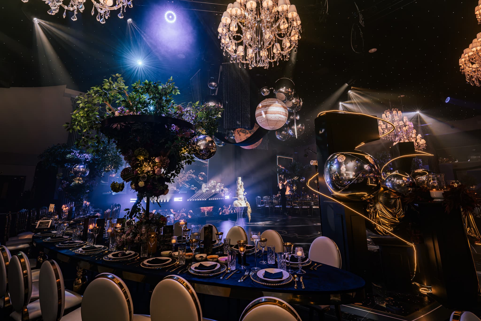 One of the black and gold tables in blue light, golden sculptures overhead, Charan and Puneet's wedding at Dallas Burston Polo Club, Kudos Music